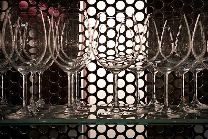 Wine glasses in front of a perforated metal wall